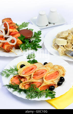 Tableau blanc avec de la nourriture de la viande, les rouleaux de saumon et de raviolis. Banque D'Images
