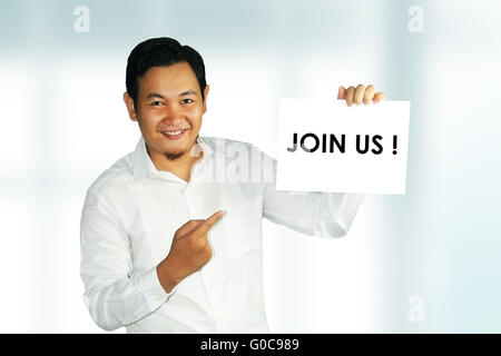 Image d'un jeune homme asiatique holding white paper avec Rejoignez-nous mots écrits sur elle sur fond lumineux Banque D'Images