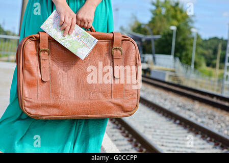 Womans mains tenant une carte et de valise à la station Banque D'Images