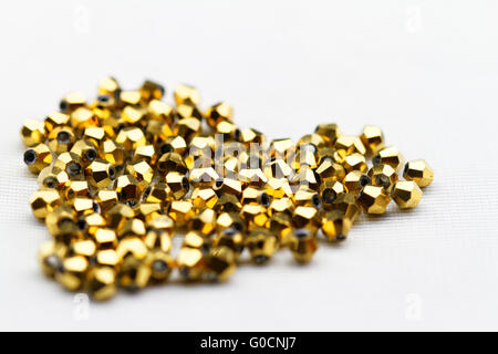 De belles perles de verre doré sur fond blanc gros plan Banque D'Images