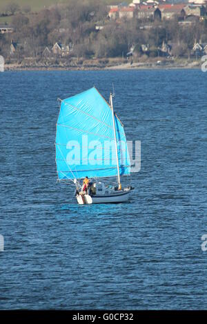 L'yacht Caber, avec un voile bleu de couleur vive, en passant Cloch Point sur le Firth of Clyde. Banque D'Images