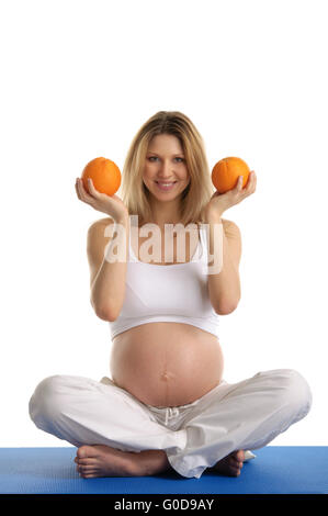 Pregnant woman practicing yoga et garde les oranges Banque D'Images