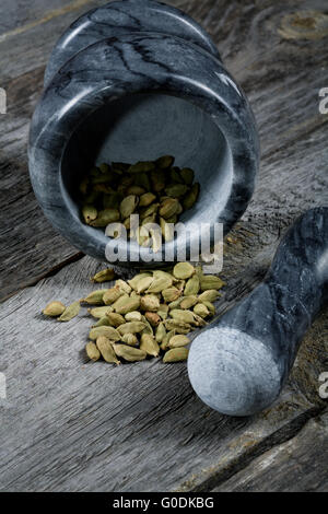 De cardamome au mortier sur une vieille table de cuisine Banque D'Images