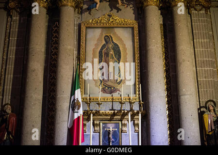 Peinture de notre-Dame de Guadalupe Cathédrale métropolitaine de Mexico // MEXICO CITY, Mexique — peinture de notre-Dame de Guadalupe exposée dans une chapelle de la Cathédrale métropolitaine de l'Assomption de la très Sainte Vierge Marie au ciel. La cathédrale métropolitaine, construite par étapes de 1573 à 1813, est la plus grande cathédrale des Amériques et sert de siège à l'archidiocèse primat de Mexico. La cathédrale dispose de 16 chapelles latérales, y compris des espaces dédiés à la dévotion à notre-Dame de Guadalupe, la sainte patronne du Mexique. Construit sur le site de l'ancien Templo Mayor aztèque, th Banque D'Images