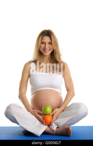 Pregnant woman practicing yoga et garde ses fruits Banque D'Images