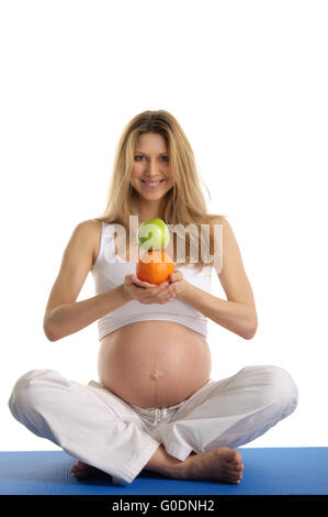 Pregnant woman practicing yoga et garde ses fruits Banque D'Images