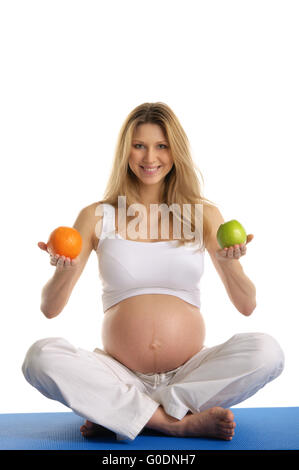 Pregnant woman practicing yoga et garde ses fruits Banque D'Images