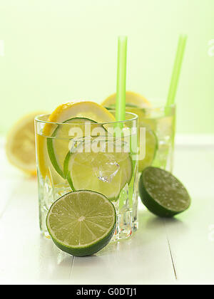 Un verre d'eau avec des limes et des tranches de citron Banque D'Images