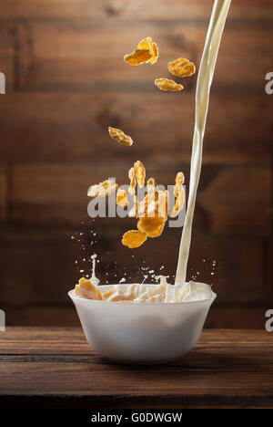 La chute de flocons de maïs avec du lait splash sur bois Banque D'Images