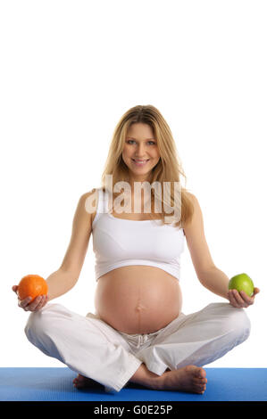 Pregnant woman practicing yoga et garde ses fruits Banque D'Images