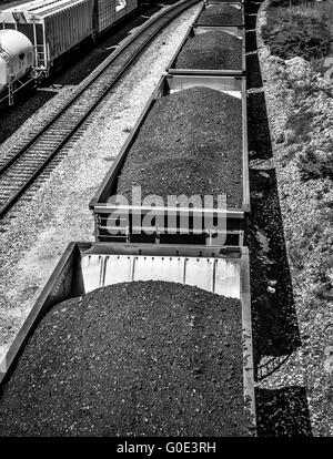 Vue de dessus de voitures de train haute empilée avec du charbon noir sur les voies ferrées le long du côté des wagons-citernes Banque D'Images