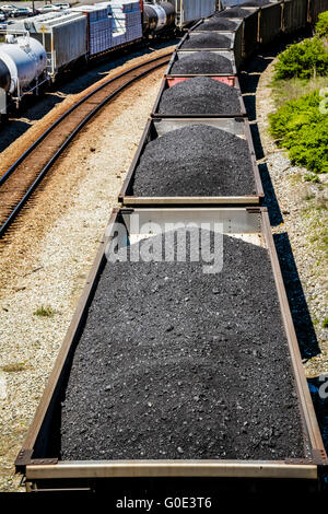 Vue de dessus de voitures de train haute empilée avec du charbon noir sur les voies ferrées le long du côté des wagons-citernes Banque D'Images