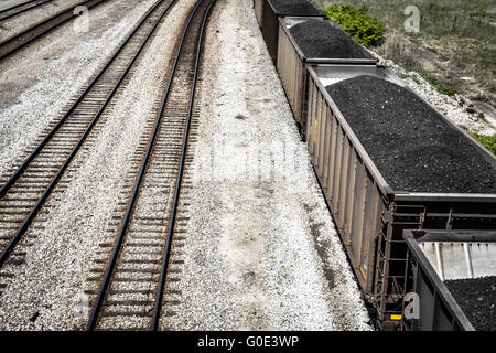 Vue de dessus de voitures de train haute empilée avec du charbon noir sur les voies ferrées le long du côté Banque D'Images