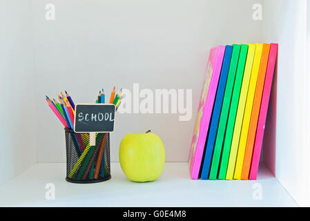 Yellow apple, crayons en titulaire et multi colored books Banque D'Images