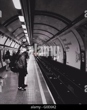 La station de métro Hyde Park avec effet noir et blanc et un tube de rouge train approchant d'un tunnel. Banque D'Images