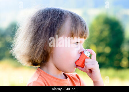 Petite fille à l'aide d'inhaler un jour ensoleillé Banque D'Images