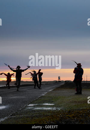 'RAG Bag Morris' marquant le jour de mai sur la chaussée de l'île Sainte de Lindisfarne, Northumberland. Chaque année, ils dansent au lever du soleil le jour de mai à un endroit différent dans le nord du Northumberland ou aux frontières écossaises. Banque D'Images