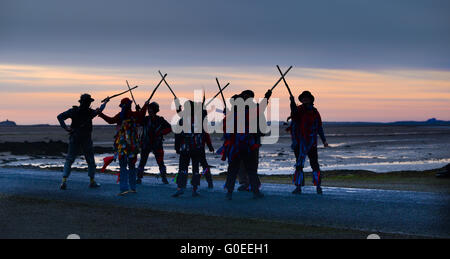 'RAG Bag Morris' marquant le jour de mai sur la chaussée de l'île Sainte de Lindisfarne, Northumberland. Chaque année, ils dansent au lever du soleil le jour de mai à un endroit différent dans le nord du Northumberland ou aux frontières écossaises. Banque D'Images