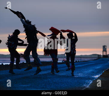 'RAG Bag Morris' marquant le jour de mai sur la chaussée de l'île Sainte de Lindisfarne, Northumberland. Chaque année, ils dansent au lever du soleil le jour de mai à un endroit différent dans le nord du Northumberland ou aux frontières écossaises. Banque D'Images