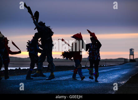 'RAG Bag Morris' marquant le jour de mai sur la chaussée de l'île Sainte de Lindisfarne, Northumberland. Chaque année, ils dansent au lever du soleil le jour de mai à un endroit différent dans le nord du Northumberland ou aux frontières écossaises. Banque D'Images