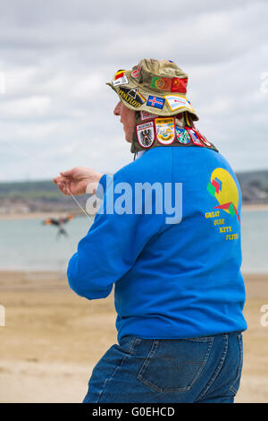 Weymouth, Dorset, Royaume-Uni, 1 mai 2016. Les visiteurs se rendent à la plage de Weymouth pour voir la magnifique exposition de cerfs-volants en vol au festival de Weymouth Kite. Homme senior tenant des cordes cerf-volant cerf-volant portant un chapeau avec des badges. Crédit : Carolyn Jenkins/Alay Live News Banque D'Images