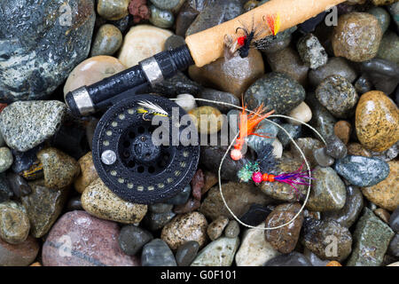 Canne à pêche à la mouche et le rabatteur de mouches sur des pierres humides Banque D'Images