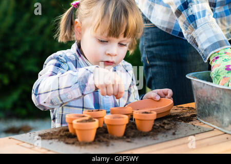 La plantation des graines de fleurs fille dans des pots avec sa mère Banque D'Images