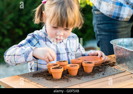 La plantation des graines de fleurs fille dans des pots avec sa mère Banque D'Images