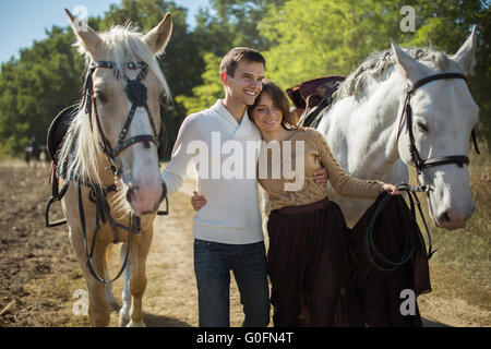 Jeune couple en train de marcher dans un endroit pittoresque avec les chevaux Banque D'Images