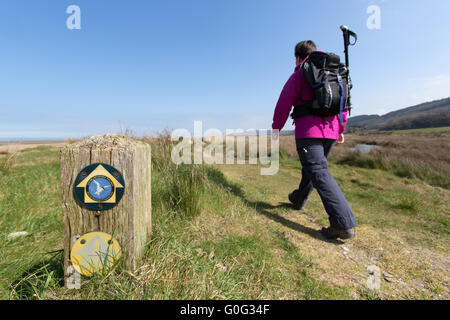 Le Pays de Galles et d'Anglesey Sentier du littoral, le Pays de Galles. Un sentier côtier d'Anglesey, signe avec une dame marcher en arrière-plan. Banque D'Images