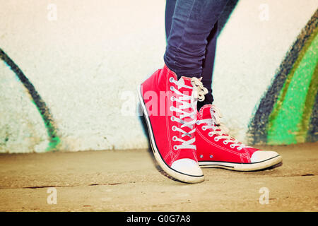 Close up of red sneakers portés par un adolescent. Mur de graffiti Grunge Banque D'Images
