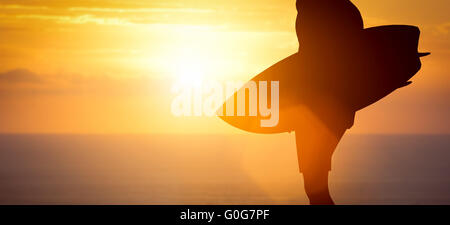 De l'article surfer sur la plage au coucher du soleil sur l'océan Banque D'Images
