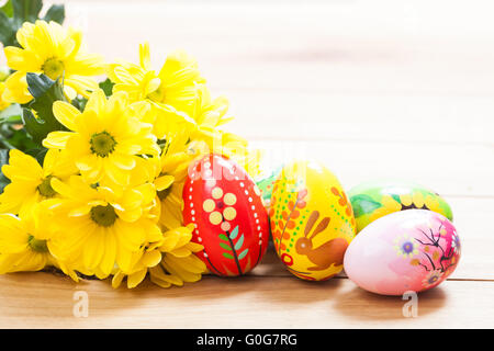 Peints à la main les oeufs de Pâques colorés et fleurs de printemps sur bois Banque D'Images