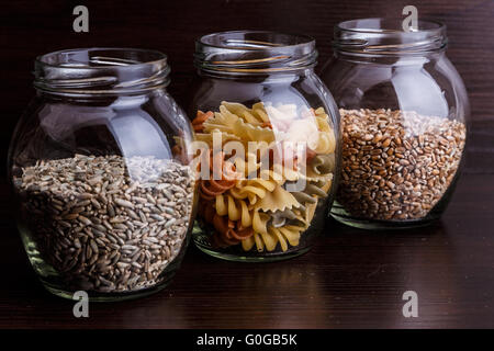 Les pâtes et les grains de blé à sec dans un bocal sur fond de bois foncé macro close-up Banque D'Images