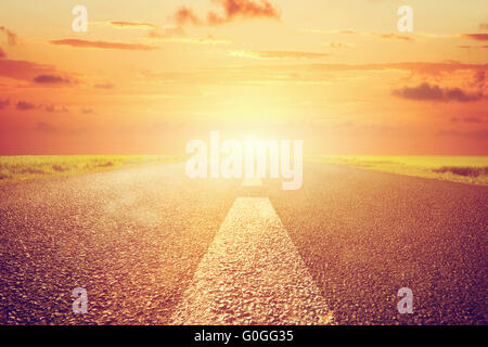 Vide longue route asphaltée vers coucher de soleil. L'échelle Banque D'Images