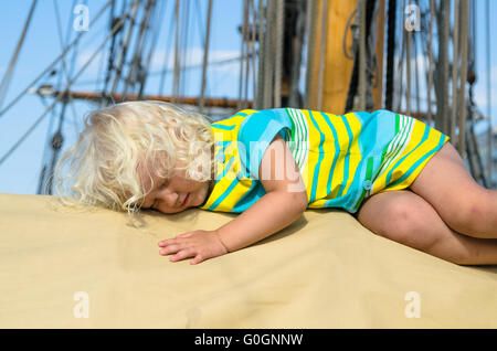 La petite fille s'endormit sur le pont d'un voilier Banque D'Images