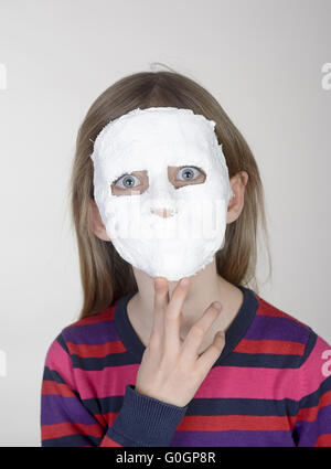 Petite fille blonde avec masque en plâtre Banque D'Images