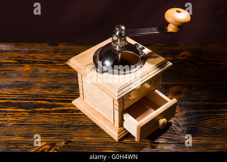 Moulin à café en bois carré avec peu d'ouvrir le tiroir et poignée en métal sur table avec fond sombre Banque D'Images