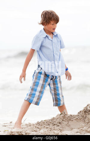Petit Garçon jouant dans le sable sur la plage Banque D'Images