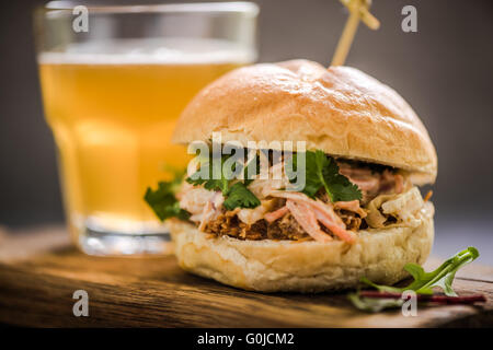 Servant des plats de brasserie, le porc bap avec salade de chou, sur planche de bois au cidre Banque D'Images