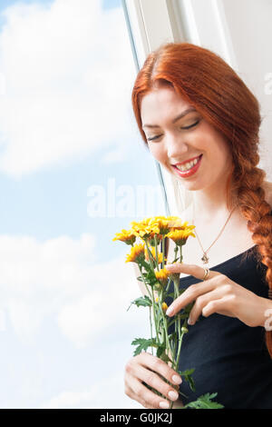 Thoughtful Woman with Flowers s'appuyant sur la fenêtre Banque D'Images