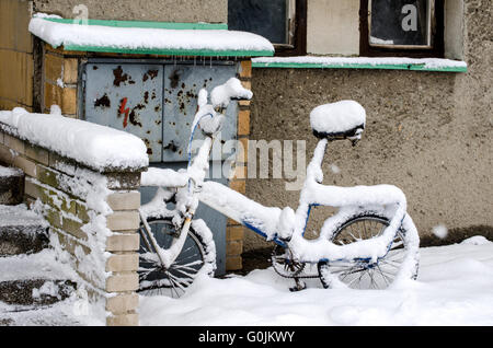 Location en hiver, debout devant un immeuble recouvert de neige Banque D'Images