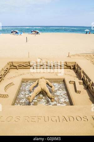 Sculptures de sable de la crise des réfugiés, Las Palmas, Gran Canaria, Îles Canaries, Espagne, 1er mai 2016. Sculpteur de sable/artiste Etual Ojeda crée une sculpture de sable stuning sur la plage de la ville, rendant hommage aux réfugiés qui ont perdu la vie sur les passages de la mer perfide. Le travail complexe montre une personne qui flotte sur l'eau entouré de barbelés avec les mots 'Imagine il n'y a pas de pays, au-dessus de sa tête. Au-dessous de ses pieds, les mots "Homenaje a los refugiados del mundo". (Hommage aux réfugiés du monde entier). Credit : Alan Dawson News/Alamy Live News Banque D'Images