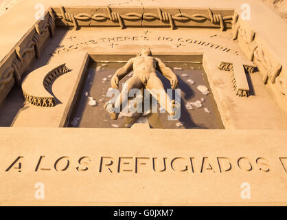 Sculptures de sable de la crise des réfugiés, Las Palmas, Gran Canaria, Îles Canaries, Espagne, 1er mai 2016. Sculpteur de sable/artiste Etual Ojeda crée une sculpture de sable stuning sur la plage de la ville, rendant hommage aux réfugiés qui ont perdu la vie sur les passages de la mer perfide. Le travail complexe montre une personne qui flotte sur l'eau entouré de barbelés avec les mots 'Imagine il n'y a pas de pays, au-dessus de sa tête. Au-dessous de ses pieds, les mots "Homenaje a los refugiados del mundo". (Hommage aux réfugiés du monde entier). Credit : Alan Dawson News/Alamy Live News Banque D'Images