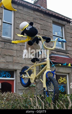 Great Ayton, North Yorkshire UK, 1 mai 2016. De nombreuses propriétés dans le village sont décorées en l'honneur du cyclisme Tour de Yorkshire, l'étape 3 de ce qui passe par le village d'aujourd'hui. À cette adresse, sur la route du Tour, un modèle original de Shaun le mouton est monté sur un vélo décoré gaiement perché dans une haie de jardin. Banque D'Images