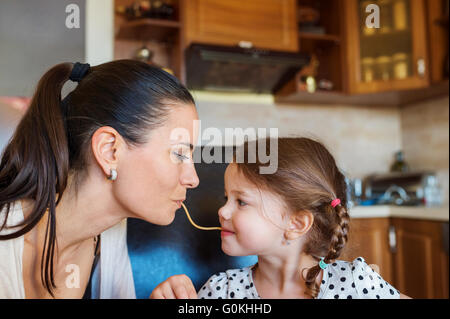 Mère et fille dans la cuisine, manger ensemble spaghetti Banque D'Images