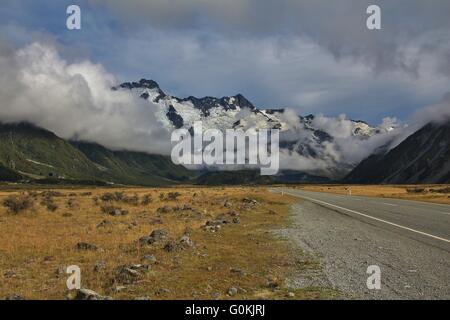 Paysage près de Mt Cook village. Montagnes couvertes de glaciers. Les nuages du matin. Route et pré. Banque D'Images