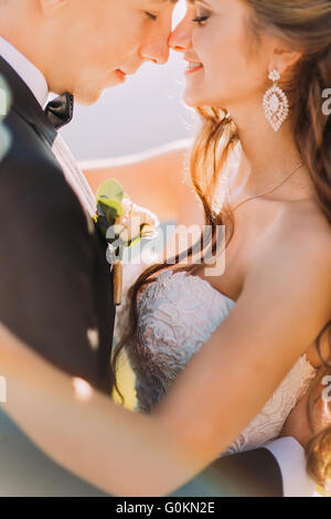 Photo en gros plan de senior jeune mariée et le marié avec bouquet rubbing noses outdoors Banque D'Images