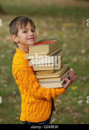 Peu heureux boy carrying pile de livres Banque D'Images