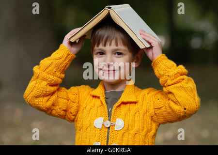 Funny boy avec livre sur sa tête Banque D'Images